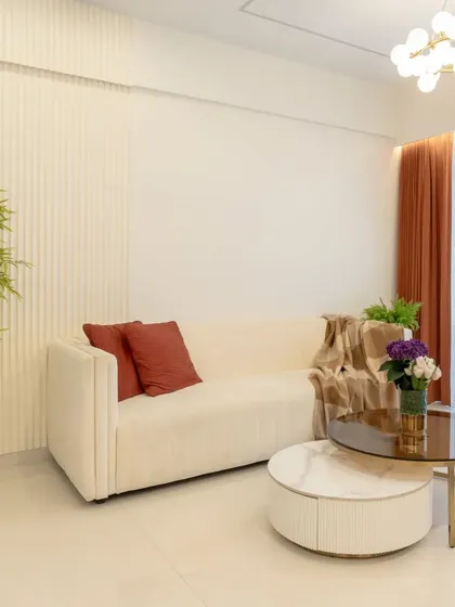 This living room is a study in serene, neutral design. A simple cream sofa is paired with a nesting coffee table and fluted wall panels for a look that is both calm and textured.