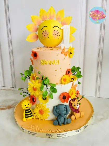 Wishing little sunshine, Saanvi, a happy first birthday! This adorable two-tiered cake is topped with a cheerful sun and surrounded by friendly animal figures.