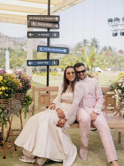 A charming photo corner at a Parisian-themed Haldi, where a couple can pose on a bench next to a signpost pointing to famous streets in Paris.