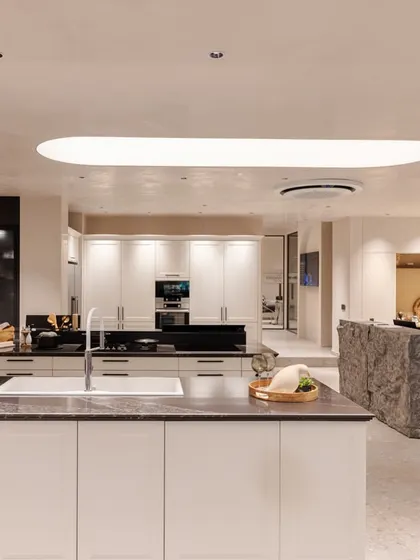 A wide view of the revamped Delhi showroom, showcasing multiple kitchen displays and a clean, modern aesthetic with soft, curved lighting elements.