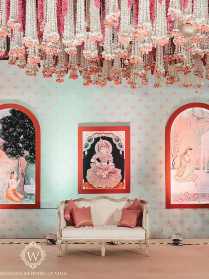 The stage for this half-saree function featured a backdrop with beautiful traditional paintings. These artworks depict the stages of a woman's life, adding a rich narrative layer to the celebration.