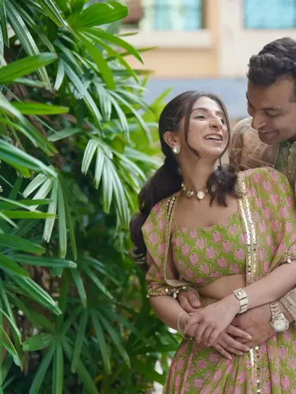 The couple sharing a laugh in a quiet corner, surrounded by lush greenery.