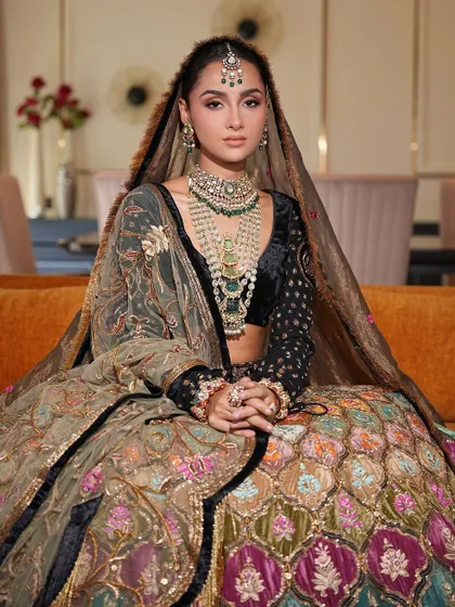 Seated gracefully, this bride showcases her unique and colorful bridal lehenga. Her makeup is subtle, with a focus on enhancing her natural features to create a look of timeless beauty.