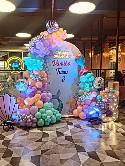 An enchanting 'under the sea' mermaid theme for Vamika's 3rd birthday. This setup uses pastel-colored balloons, a large marquee number '3', and seashell props to create a magical ocean vibe.