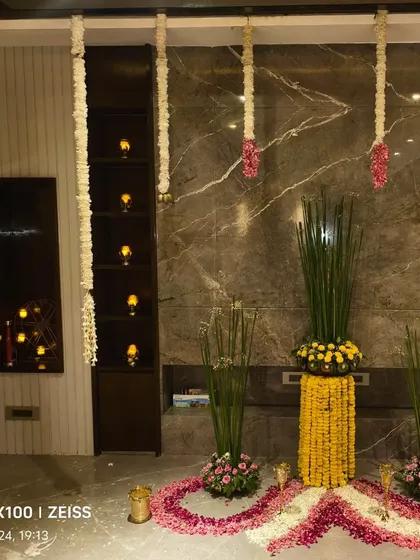 A corner of a home decorated for Diwali with traditional flower arrangements, hanging garlands, and candles.