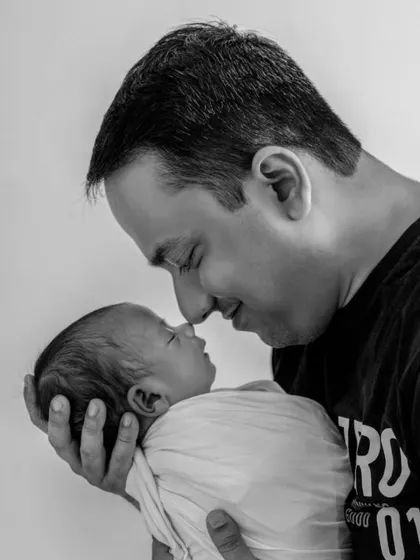 An intimate black and white portrait of a father and his newborn baby, nose to nose, capturing the profound and gentle connection in those very first days.