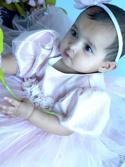 A sweet baby girl in a pink tulle dress holds a tulip, surrounded by flowers. This themed baby photoshoot showcases our use of props and soft lighting to create a dreamy atmosphere.