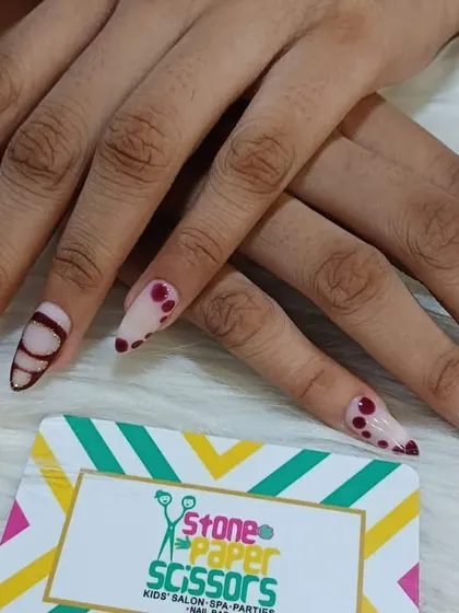 This abstract design on long stiletto nails uses shades of pink and burgundy. I created different patterns on each nail, including stripes, dots, and floral-like shapes.