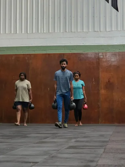 A group of athletes engaged in a farmer's carry. This is a great example of how we incorporate functional strength training into our group sessions.
