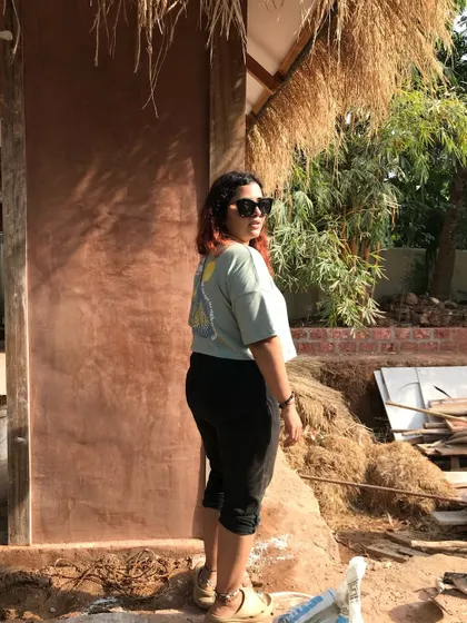 This is me, standing proudly in front of a perfectly plastered cob wall. It’s breathable, non-toxic, and stone-strong, representing the sustainable, healthy lifestyle I advocate for.