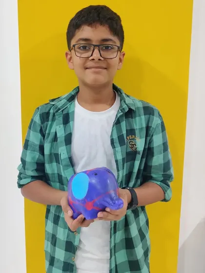 A young boy proudly holds up the elephant planter he painted at an animal-themed art party.