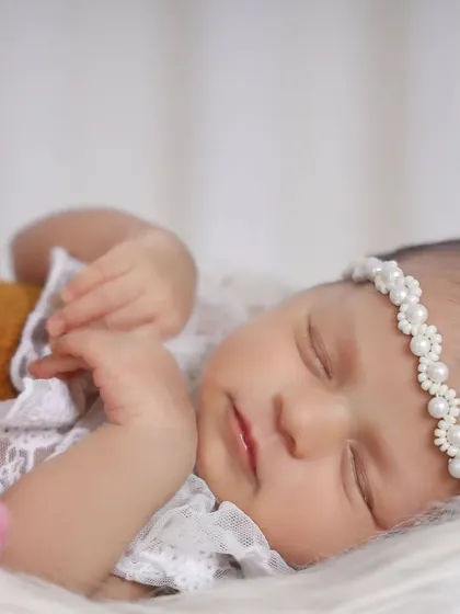 Sometimes, the most beautiful photos are the simplest. This close-up highlights the delicate features of a sleeping newborn, from her soft skin to the tiny pearls on her headband. It’s these small details I want you to remember forever.