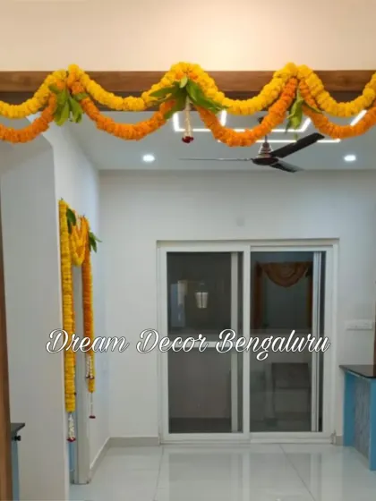 Simple and traditional decor for a housewarming ceremony. Marigold and mango leaf garlands (thoranam) are used to decorate the main doorway, a classic symbol of welcome and prosperity.