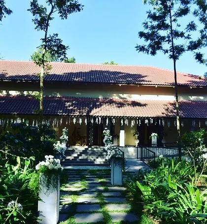 The entrance to a beautiful, traditional house set in lush greenery, decorated simply for an engagement ceremony.