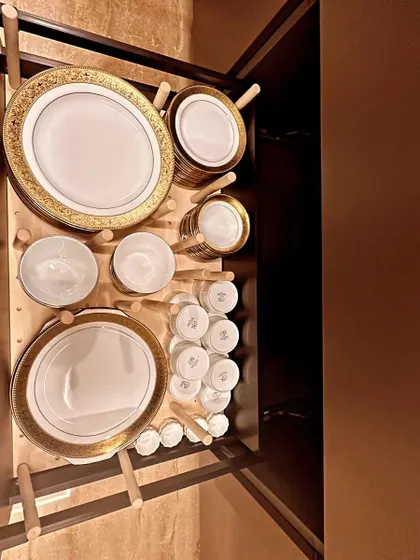 A top-down view of a perfectly organized crockery drawer. Using pegboard-style dividers keeps fine china safe and easy to access.
