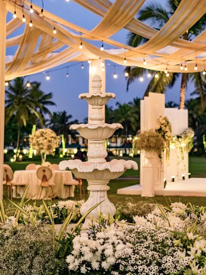 The fountain viewed from a distance at dusk, with the warm glow of the reception lights in the background. This image captures the overall enchanting atmosphere of the evening.
