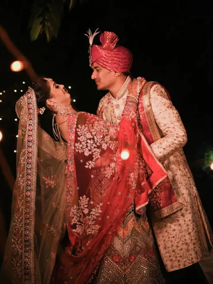 A dynamic and romantic pose, capturing the couple in a dance-like embrace under the soft glow of string lights.