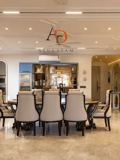 This spacious dining room features a large table, elegant chairs, and a custom crockery unit, all under a beautifully detailed coffered ceiling.