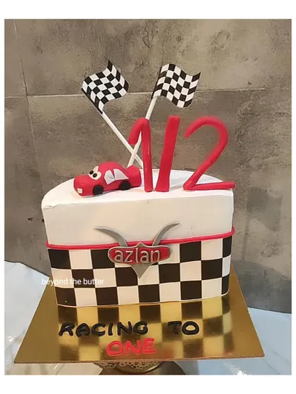 Racing to one! This "halfway to one" cake is perfect for a six month celebration, featuring a Lightning McQueen theme with checkered flags and a mini race car.