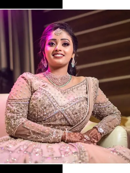 An elegant portrait of the bride seated in her heavily embellished reception lehenga.