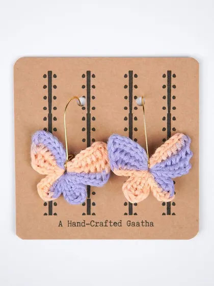A product shot of the peach and lilac butterfly earrings, showing the delicate craftsmanship and beautiful color pairing.