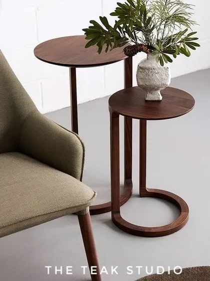 A pair of minimalist nesting side tables. The C-shaped design of the smaller table allows it to tuck neatly beside a chair or sofa, while the dark wood finish adds a touch of warmth and sophistication.