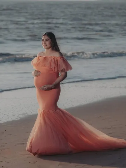 A serene portrait of an expecting mother on the beach in our peach mermaid gown. The soft waves and gentle smile make for a timeless and beautiful memory.