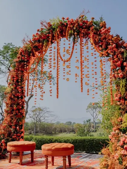 A beautiful outdoor Mehendi setup with a floral arch made of orange marigolds and hanging garlands.