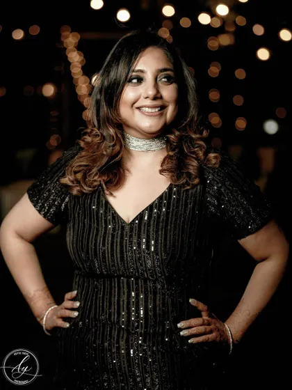 A confident and happy portrait of a guest at a cocktail party. The bokeh from the background lights adds a festive and glamorous feel to this candid shot.