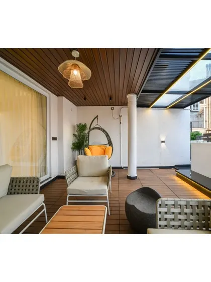 Relax in this stunning outdoor sitting area on a spacious private balcony, a peaceful sanctuary featuring cozy seating, a hanging swing chair, and vibrant greenery.