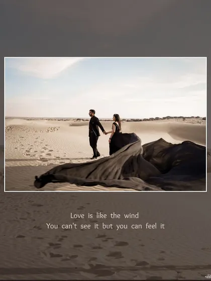 A dramatic scene in the Jaisalmer desert, with the couple standing together as the bride's long black gown flows in the wind across the sand dunes.