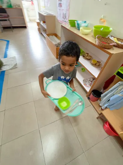 Responsibility is woven into every part of our day. After finishing his snack, this child carefully carries his tray to the cleaning area, demonstrating care for the materials and the classroom community.