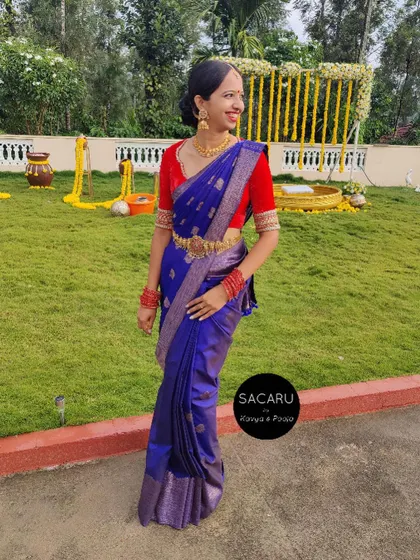 A full-length view of our client Thanni in her vibrant red velvet blouse and blue silk saree, a perfect example of contrast styling.