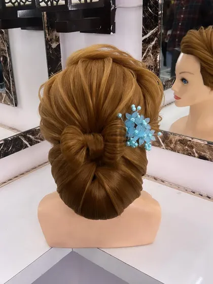 A finished look of the low bun with a bow, decorated with a delicate blue floral accessory.