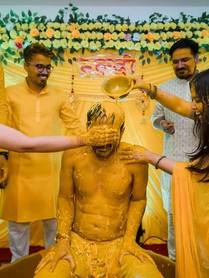 A fun moment where a bowl of water is poured over the groom's head, capturing the playful spirit of his friends and family.