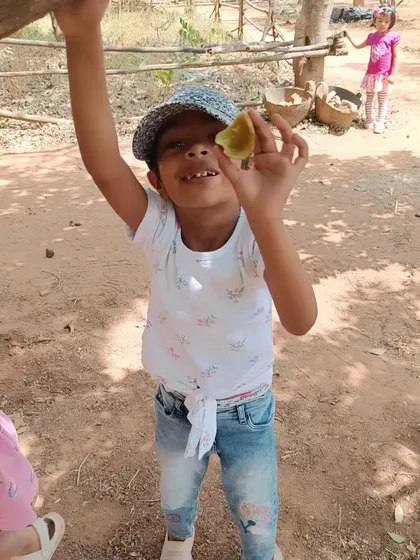 A child shows off a piece of fruit found during our farm exploration. Every little discovery is a moment of pride and learning.