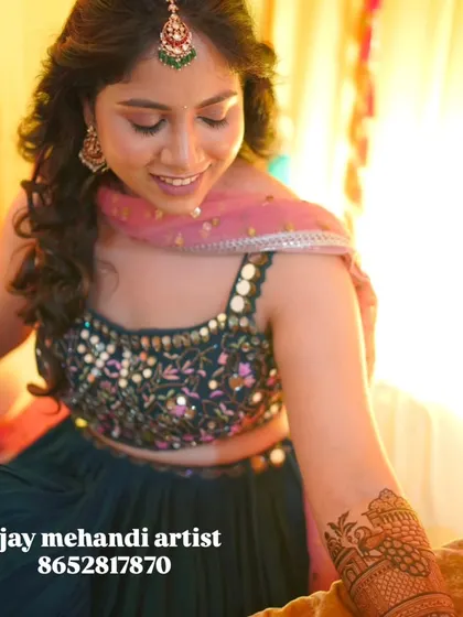 A candid moment of a bride smiling, with a close-up on the detailed mehndi on her forearm.