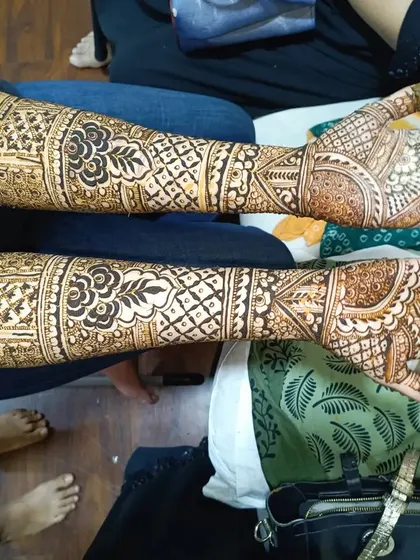 A horizontal view of a complete bridal mehendi application. The design flows beautifully from the fingertips up the arms, with repeating motifs that create a sense of harmony.