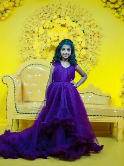A full-length shot of a young girl in a beautiful purple trail gown, posing confidently in our studio.