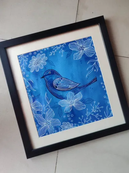 This framed piece, 'Blue Birdie', combines a rich blue watercolor background with intricate white floral line art. The detailed patterns on the bird make it a standout piece of decor.
