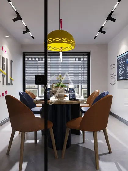 Looking into the meeting room through its glass partition. This view highlights the "Stay Humble, Hustle Hard" wall art and the layering of different light fixtures, including track lighting and colorful pendants.