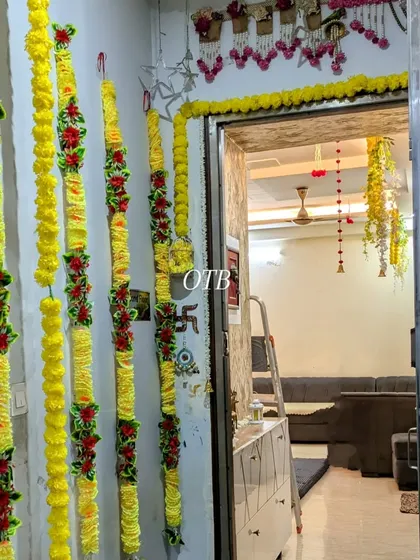 Decorating the entrance to the home with traditional marigold flower strings to welcome guests into the 'shadi wala ghar'.