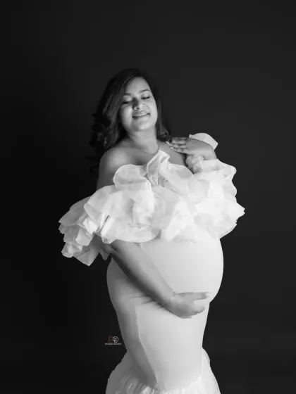 A serene and beautiful black and white portrait. The soft light and elegant pose create a timeless image that celebrates the beauty of the female form during pregnancy.