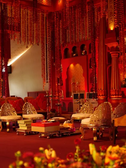 The seating area within the mandap, featuring ornate chairs and traditional elements, all bathed in a warm red glow.
