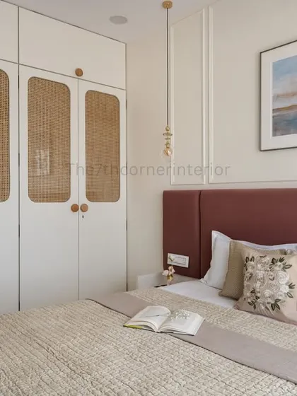 A wider shot of the bedroom, showing how the cane-detailed wardrobe complements the dusty rose headboard and neutral tones, creating a space that is both stylish and texturally rich.