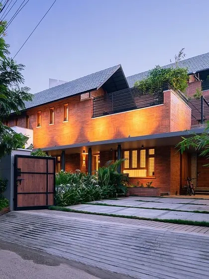 The entrance to this contemporary brick home is enhanced by our landscape design. We used a mix of broadleaf plants and pavers to create a modern, low-maintenance entryway that complements the home's unique architectural style.