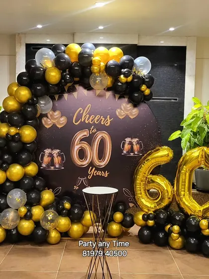 A "Cheers to 60 Years" theme party with a custom backdrop and a black and gold balloon arch.