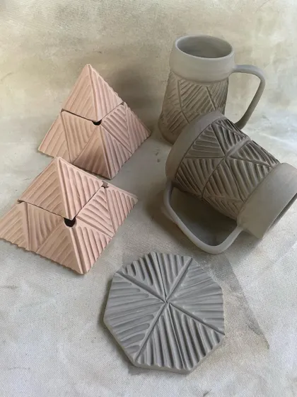 Greenware from a professional course student's collection, featuring carved beer mugs and pyramid-shaped lidded boxes.