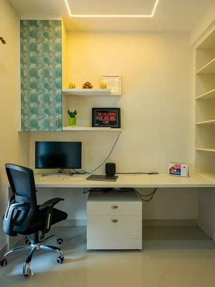 This compact home office nook uses patterned wallpaper on the storage units to add personality, with a clean white desk and open shelving for a functional and creative workspace.