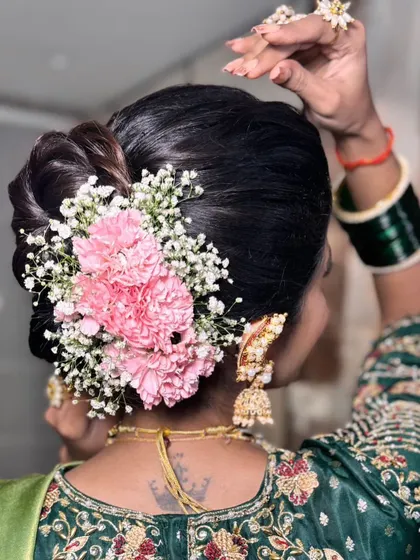 I love blending modern textures with traditional elements. This soft updo is adorned with pink carnations and baby's breath, creating a fresh take on the classic 'khopa' style.